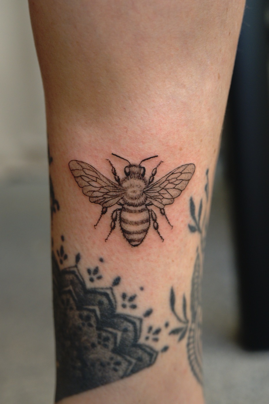 Tatouage fine line d'une abeille, mollet
